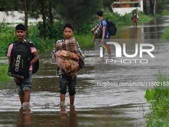 People wade through floodwater in Feni, Chittagong, Bangladesh, on August 23, 2024. (