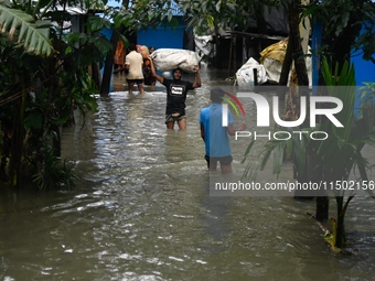 Local residents shift to temporary shelter homes as floodwater rises in their homes in Feni, Chittagong, Bangladesh, on August 23, 2024. (