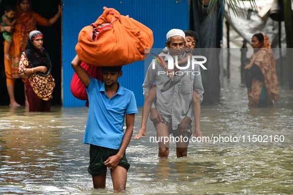 People wade through floodwater in Feni, Chittagong, Bangladesh, on August 23, 2024. 