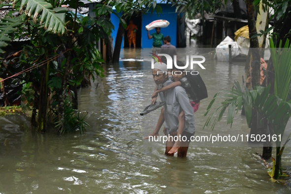 People wade through floodwater in Feni, Chittagong, Bangladesh, on August 23, 2024. 