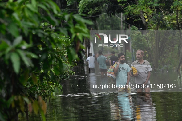 People wade through floodwater in Feni, Chittagong, Bangladesh, on August 23, 2024. 