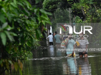 People wade through floodwater in Feni, Chittagong, Bangladesh, on August 23, 2024. (