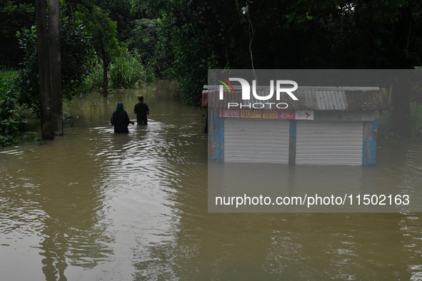 People wade through floodwater in Feni, Chittagong, Bangladesh, on August 23, 2024. 