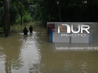 People wade through floodwater in Feni, Chittagong, Bangladesh, on August 23, 2024. (