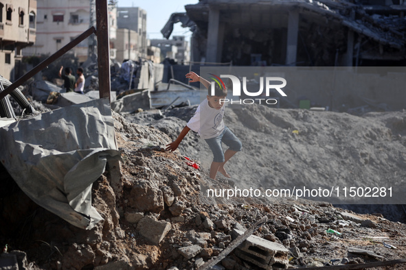 A young Palestinian boy walks near a building destroyed by an Israeli airstrike in the Nuseirat refugee camp in central Gaza Strip on August...