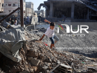 A young Palestinian boy walks near a building destroyed by an Israeli airstrike in the Nuseirat refugee camp in central Gaza Strip on August...