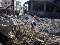 A young Palestinian boy walks near a building destroyed by an Israeli airstrike in the Nuseirat refugee camp in central Gaza Strip on August...