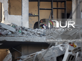 A Palestinian girl stands in despair on the balcony of a damaged apartment near a building destroyed by an Israeli airstrike in the Nuseirat...