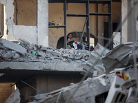 A Palestinian girl stands in despair on the balcony of a damaged apartment near a building destroyed by an Israeli airstrike in the Nuseirat...