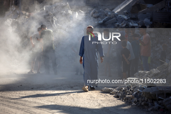 Palestinians gather near a building destroyed by an Israeli airstrike in the Nuseirat refugee camp in central Gaza Strip on August 23, 2024,...