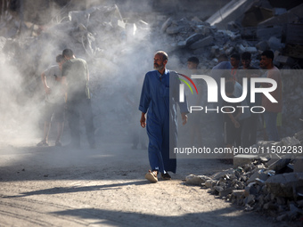 Palestinians gather near a building destroyed by an Israeli airstrike in the Nuseirat refugee camp in central Gaza Strip on August 23, 2024,...