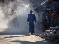 Palestinians gather near a building destroyed by an Israeli airstrike in the Nuseirat refugee camp in central Gaza Strip on August 23, 2024,...