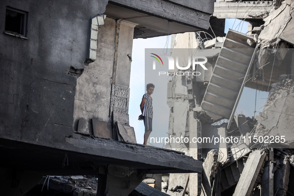 A young Palestinian boy stands near a building destroyed by an Israeli airstrike in the Nuseirat refugee camp in central Gaza Strip on Augus...