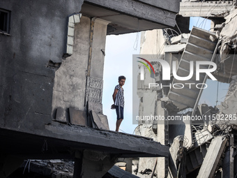 A young Palestinian boy stands near a building destroyed by an Israeli airstrike in the Nuseirat refugee camp in central Gaza Strip on Augus...