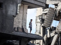 A young Palestinian boy stands near a building destroyed by an Israeli airstrike in the Nuseirat refugee camp in central Gaza Strip on Augus...