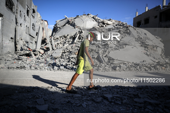 A young Palestinian boy walks near a building destroyed by an Israeli airstrike in the Nuseirat refugee camp in central Gaza Strip on August...