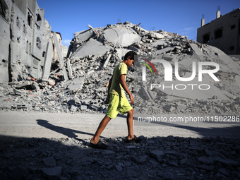 A young Palestinian boy walks near a building destroyed by an Israeli airstrike in the Nuseirat refugee camp in central Gaza Strip on August...