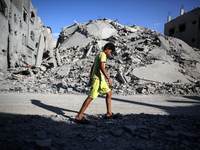 A young Palestinian boy walks near a building destroyed by an Israeli airstrike in the Nuseirat refugee camp in central Gaza Strip on August...