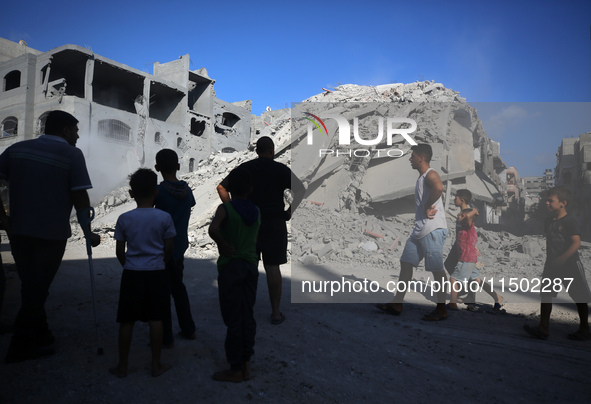 Palestinians gather near a building destroyed by an Israeli airstrike in the Nuseirat refugee camp in central Gaza Strip on August 23, 2024,...