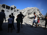 Palestinians gather near a building destroyed by an Israeli airstrike in the Nuseirat refugee camp in central Gaza Strip on August 23, 2024,...