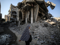 A Palestinian woman walks near a building destroyed by an Israeli airstrike in the Nuseirat refugee camp in central Gaza Strip on August 23,...