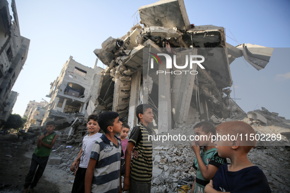 Palestinians gather near a building destroyed by an Israeli airstrike in the Nuseirat refugee camp in central Gaza Strip on August 23, 2024,...