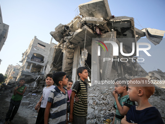 Palestinians gather near a building destroyed by an Israeli airstrike in the Nuseirat refugee camp in central Gaza Strip on August 23, 2024,...