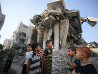 Palestinians gather near a building destroyed by an Israeli airstrike in the Nuseirat refugee camp in central Gaza Strip on August 23, 2024,...