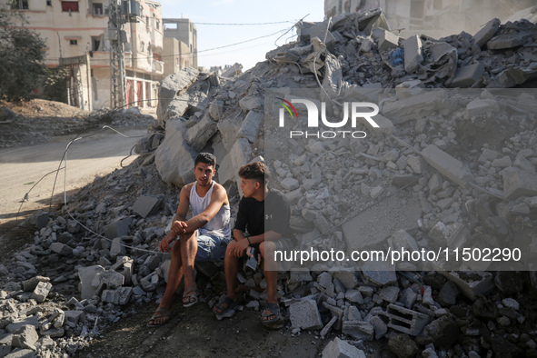 Palestinians gather near a building destroyed by an Israeli airstrike in the Nuseirat refugee camp in central Gaza Strip on August 23, 2024,...