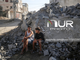 Palestinians gather near a building destroyed by an Israeli airstrike in the Nuseirat refugee camp in central Gaza Strip on August 23, 2024,...