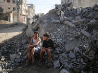 Palestinians gather near a building destroyed by an Israeli airstrike in the Nuseirat refugee camp in central Gaza Strip on August 23, 2024,...