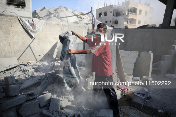 A Palestinian girl stands in despair on the balcony of a damaged apartment near a building destroyed by an Israeli airstrike in the Nuseirat...