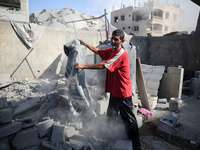 A Palestinian girl stands in despair on the balcony of a damaged apartment near a building destroyed by an Israeli airstrike in the Nuseirat...