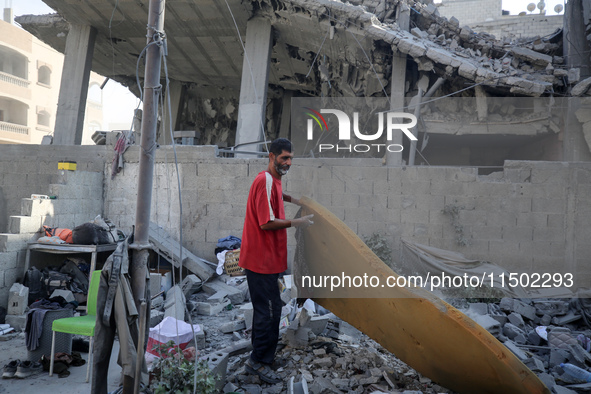 A Palestinian girl stands in despair on the balcony of a damaged apartment near a building destroyed by an Israeli airstrike in the Nuseirat...