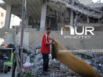 A Palestinian girl stands in despair on the balcony of a damaged apartment near a building destroyed by an Israeli airstrike in the Nuseirat...