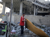 A Palestinian girl stands in despair on the balcony of a damaged apartment near a building destroyed by an Israeli airstrike in the Nuseirat...