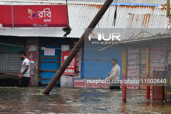 People wade through floodwater in Feni, Chittagong, Bangladesh, on August 23, 2024. 