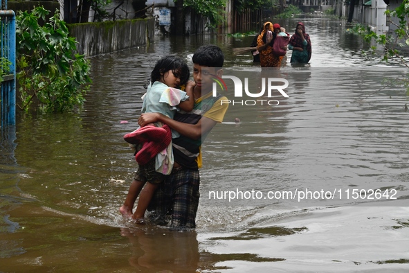 People wade through floodwater in Feni, Chittagong, Bangladesh, on August 23, 2024. 