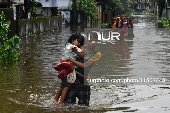 People wade through floodwater in Feni, Chittagong, Bangladesh, on August 23, 2024. 