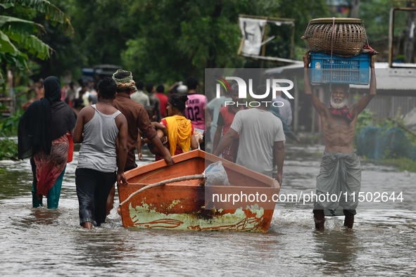 People wade through floodwater in Feni, Chittagong, Bangladesh, on August 23, 2024. 