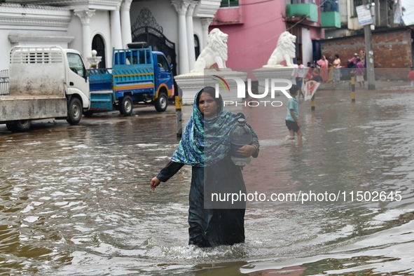 People wade through floodwater in Feni, Chittagong, Bangladesh, on August 23, 2024. 