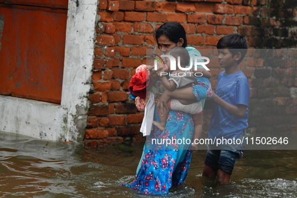 People wade through floodwater in Feni, Chittagong, Bangladesh, on August 23, 2024. 