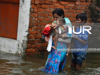 People wade through floodwater in Feni, Chittagong, Bangladesh, on August 23, 2024. (