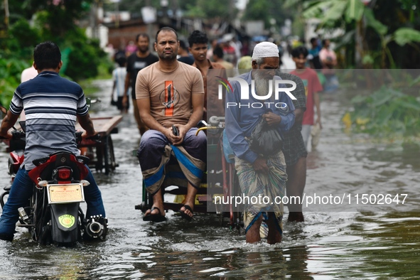 People wade through floodwater in Feni, Chittagong, Bangladesh, on August 23, 2024. 