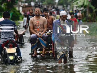 People wade through floodwater in Feni, Chittagong, Bangladesh, on August 23, 2024. (