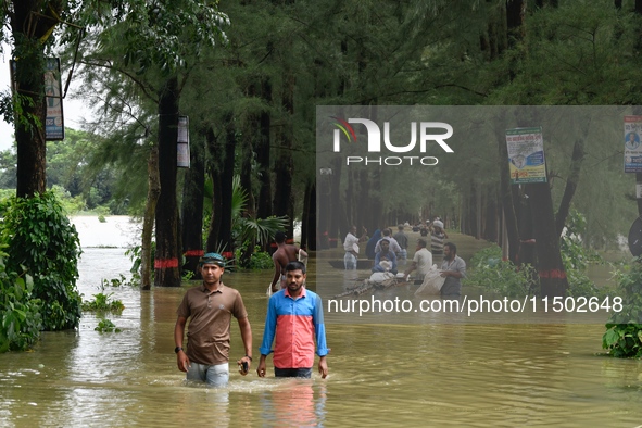 People wade through floodwater in Feni, Chittagong, Bangladesh, on August 23, 2024. 