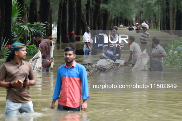 People wade through floodwater in Feni, Chittagong, Bangladesh, on August 23, 2024. 