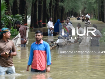 People wade through floodwater in Feni, Chittagong, Bangladesh, on August 23, 2024. (