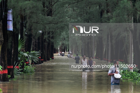 People wade through floodwater in Feni, Chittagong, Bangladesh, on August 23, 2024. 