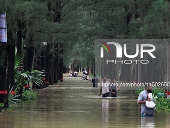 People wade through floodwater in Feni, Chittagong, Bangladesh, on August 23, 2024. (